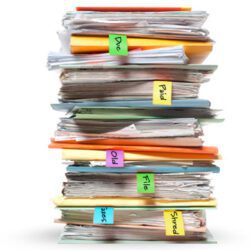 Stacks of files thick with papers and labeled with sticky notes.