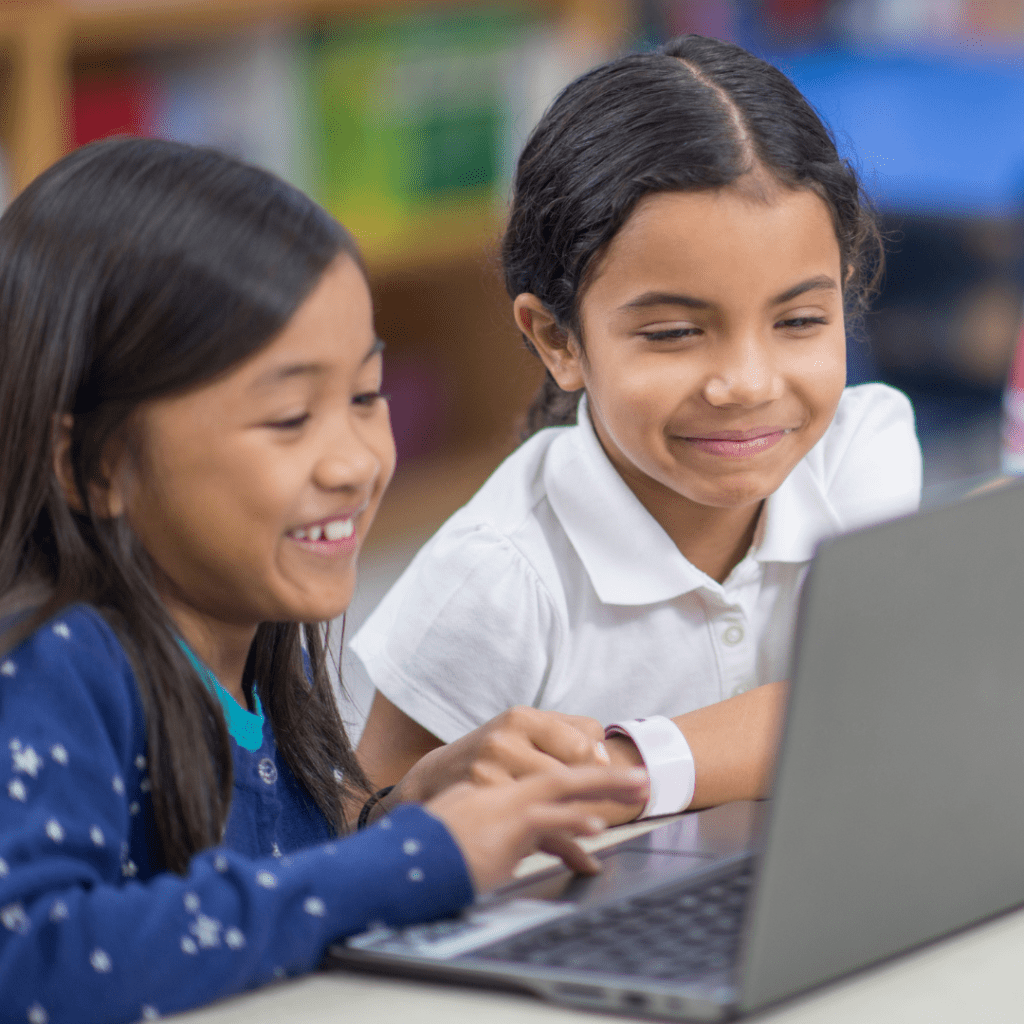 Two young girls using a laptop.