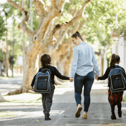 A mother holds hands with her two children as they walk to school.