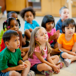 A group of children sit and listen.