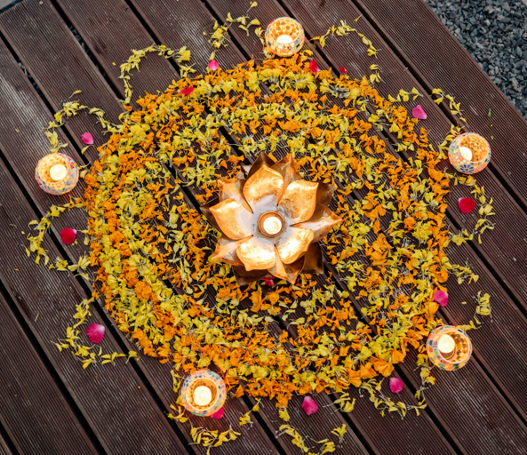 Rangoli design with flower petals and candles.