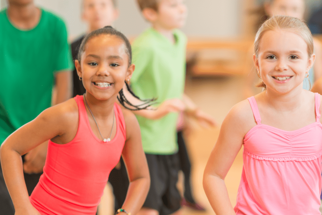 Group of children dancing with close up of two girls in front.