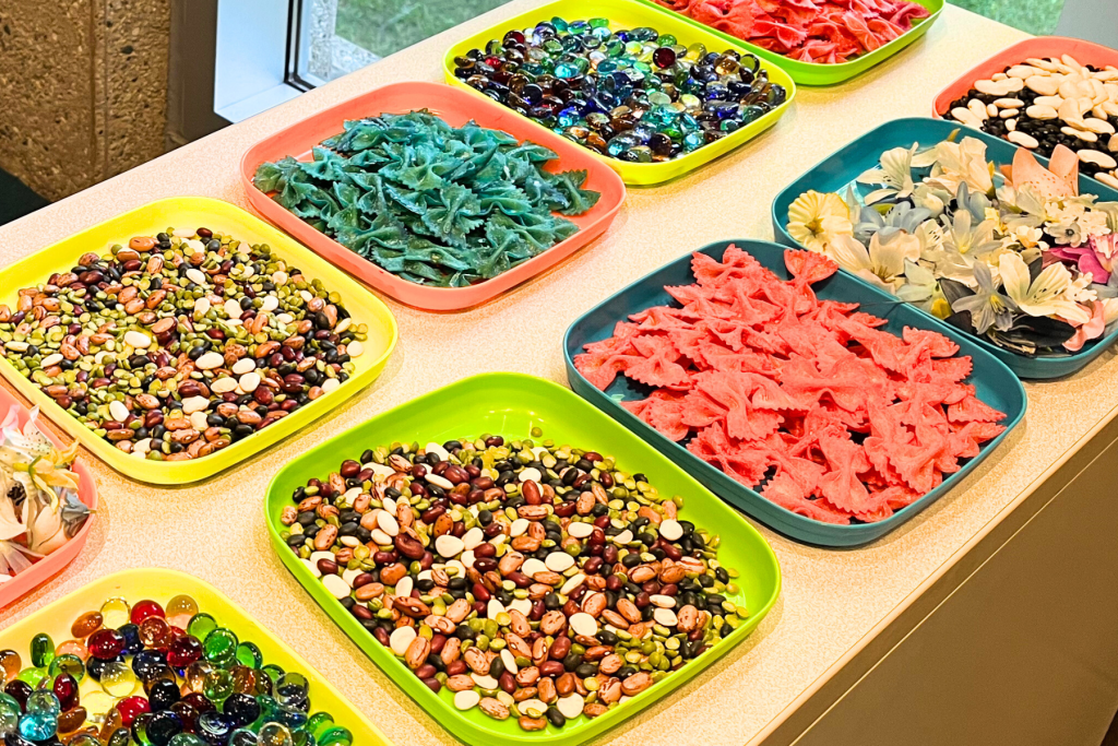Bins of dried beans, dried pasta, colorful glass stones, and fake flowers.