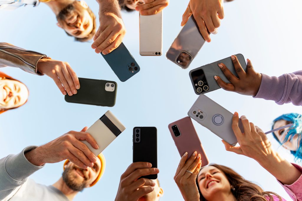 Group of people holding their cell phones out, creating a circle of phones.